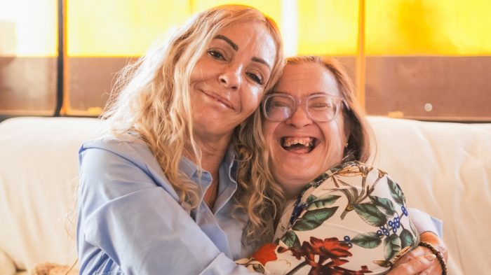 Volunteer,Embracing,A,Happy,Disabled,Woman,With,Down,Syndrome,,Sitting