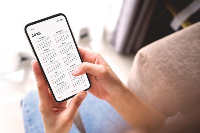 Businesswoman,Using,Smartphone,With,Monthly,Calendar,To,Plan,2025,Activities.